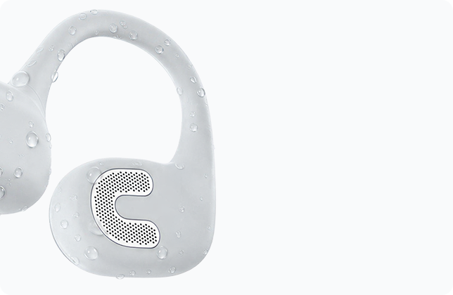 Close-up of the white AirWave Pro2 ear hook with water droplets, showing the headphones being rinsed clean after training.