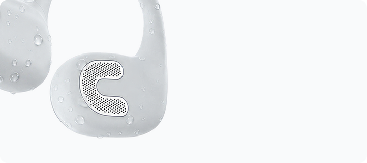 Close-up of the white AirWave Pro2 ear hook with water droplets, showing the headphones being rinsed clean after training.