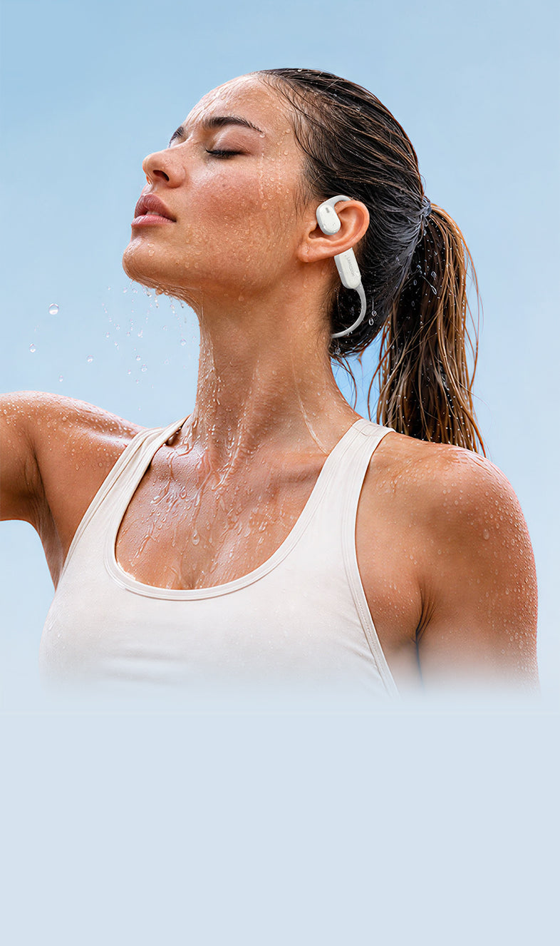 Man running on a wet outdoor path while wearing white AirWave Pro2 open-ear sports headphones.
